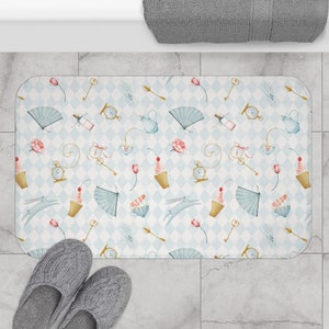May include: A blue and white bath mat with a checkered pattern and a whimsical design featuring teacups, clocks, keys, and cupcakes. The design is inspired by Alice in Wonderland.