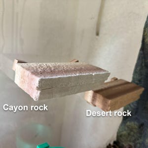 May include: Two pieces of rock, one labeled "Canyon rock" and the other labeled "Desert rock". The canyon rock is a light brown color and has a rough texture. The desert rock is a darker brown color and has a smoother texture.