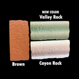 K&ouml;nnte beinhalten: Drei strukturierte Gesteinsproben in den Farben Braun, Gr&uuml;n und Off-White. Die braune Probe ist mit "Brown" beschriftet. Die gr&uuml;ne Probe ist mit "Valley Rock" beschriftet, und die cremefarbene Probe ist mit "Cayon Rock" beschriftet. Die Worte "NEW COLOR" stehen &uuml;ber "Valley Rock".