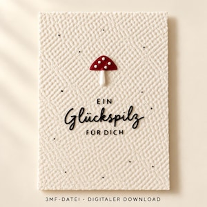 May include: A rectangular off-white card with a textured, cross-hatched surface. Centered at the top is a small red mushroom with white spots. Below the mushroom, the black text reads "EIN Glückspilz FÜR DICH". Small black dots are scattered.