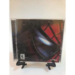 May include: A clear plastic jewel case containing a video game disc, featuring a close-up graphic of a red and black spider-themed mask with a large reflective eye lens. The cover includes the Activision logo and an ESRB Everyone rating symbol.