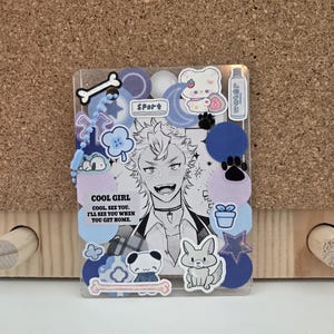 May include: Clear, rectangular phone case decorated with stickers. The stickers include a black and white anime-style character, cartoon animals, and the text "COOL GIRL. COOL. SEE YOU. I'LL SEE YOU WHEN YOU GET HOME."