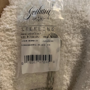 May include: A packaged Gorham Sterling silver spoon. The packaging includes the Gorham logo, the word "STERLING", a date, lot number, item number, and the text "STRASBOURG PLACE FK". The spoon is in a clear plastic bag.
