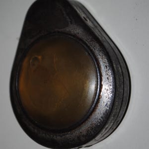 Może przedstawiać: Srebrny, metalowy zegarek kieszonkowy w stylu vintage z okrągłą, przezroczystą tarczą. Zegarek ma pętelkę na górze do zawieszenia.