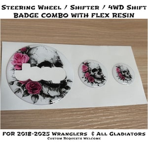May include: A set of three resin badges featuring a skull design with pink roses. The largest badge has a Jeep logo cutout. The text at the top reads "STEERING WHEEL / SHIFTER / 4WD SHIFT BADGE COMBO WITH FLEX RESIN". The bottom text reads "FOR 2018-2025 WRANGLERS & ALL GLADIATORS".