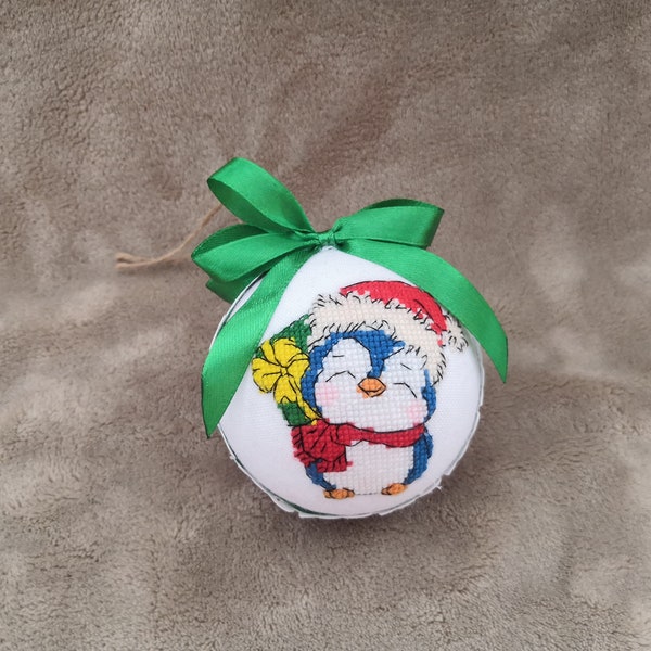 Holiday ornament with a penguin hiding a gift behind its back