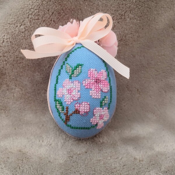 Easter egg with delicate spring flowers on a blue background