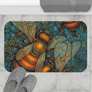 May include: A rectangular bath mat featuring a detailed illustration of bees with orange and brown bodies and translucent wings. The background is a teal honeycomb pattern. Gray slippers are in the foreground.
