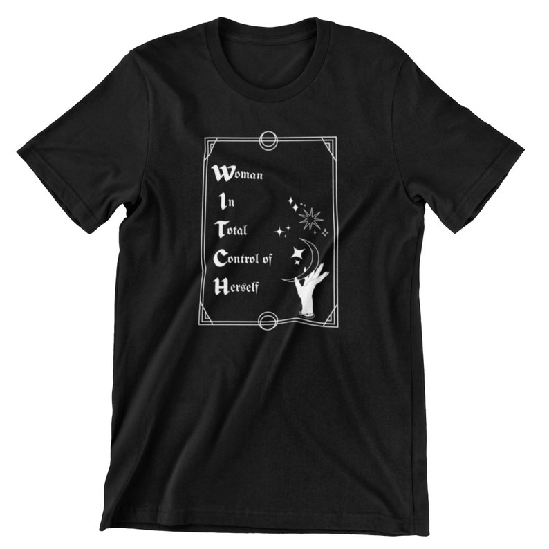 Pode incluir: Camiseta preta com um gr&aacute;fico branco. O gr&aacute;fico apresenta as palavras "Woman in Total Control of Herself" em uma fonte decorativa, juntamente com elementos celestiais como estrelas, uma lua crescente e uma m&atilde;o.