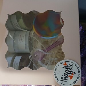 K&ouml;nnte beinhalten: Eine Geschenkbox mit einem wellenf&ouml;rmigen Fenster, das mehrere Gl&auml;ser, eine farbenfrohe Sch&uuml;ssel und einen L&ouml;ffel zeigt. Die Gl&auml;ser sind beschriftet. Die Box ist mit Papierf&uuml;llung und einem Aufkleber mit der Aufschrift "Thank You" und "Handmade with Love" verziert.