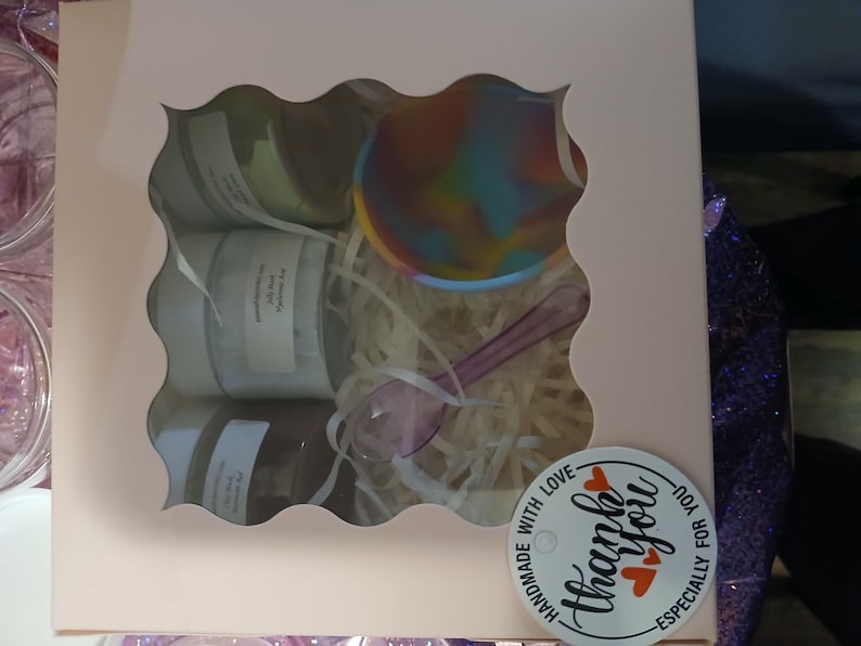 K&ouml;nnte beinhalten: Eine Geschenkbox mit einem wellenf&ouml;rmigen Fenster, das mehrere Gl&auml;ser, eine farbenfrohe Sch&uuml;ssel und einen L&ouml;ffel zeigt. Die Gl&auml;ser sind beschriftet. Die Box ist mit Papierf&uuml;llung und einem Aufkleber mit der Aufschrift "Thank You" und "Handmade with Love" verziert.