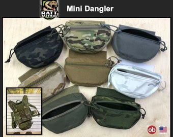 May include: A set of seven Mini Dangler pouches in various camouflage patterns, including black, green, brown, and white. The pouches are made by RATT Tactical Combat Gear and are designed to be attached to a belt or vest. The pouches have a zippered opening and a drawstring closure. The pouches are made of durable nylon and are designed to be lightweight and easy to carry.