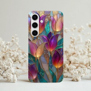May include: A phone case featuring a stained-glass design of tulips in shades of purple, pink, and gold. The case has a glossy finish and a camera cutout. The floral pattern is set against a teal and gold background.
