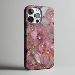 May include: A phone case featuring a floral design in shades of pink, purple, and gold. The case has a glossy finish and is adorned with sparkling accents. The design includes large, stylized flowers and intricate details.