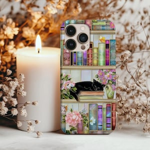 May include: A phone case featuring a colorful bookshelf design with a sleeping black cat. The case has a floral and butterfly motif, with a lit white candle in the background.