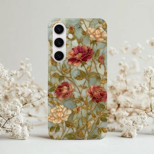 May include: A phone case featuring a floral design with red, pink, and cream-colored roses. The roses are set against a light blue background with gold-colored accents. The case has a glossy finish and a camera cutout.