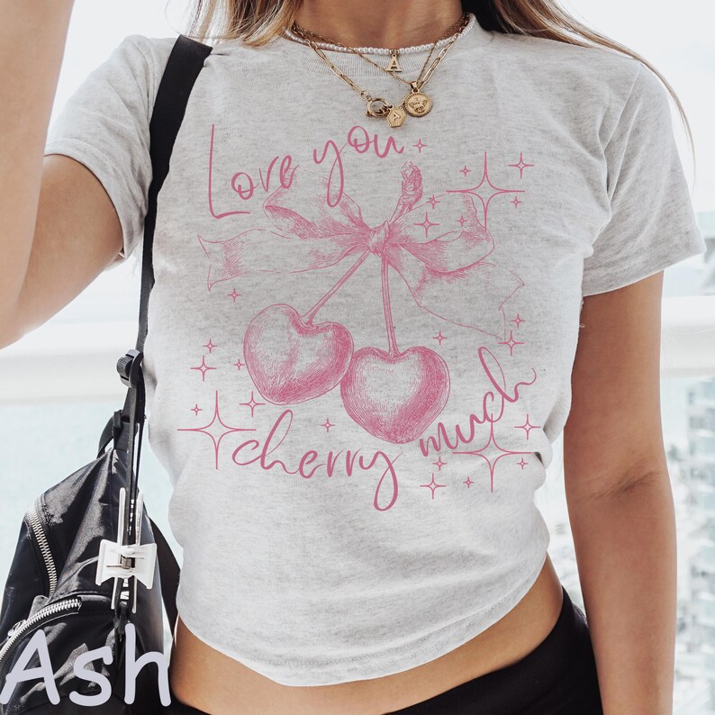 May include: A light gray t-shirt with a pink cherry graphic and the words "Love you cherry much". The design includes two cherries, a bow, and starbursts.