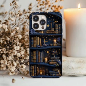 May include: A navy blue phone case featuring a bookshelf design with books, candles, and stars. The case has a 3D effect, with the books and shelves appearing to be raised. The design includes gold accents and a floral arrangement.