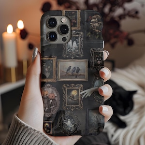 Op de afbeelding: Zwarte telefoonhoes met een collage van ingelijste vintage kunst. De kunstwerken bevatten afbeeldingen van geesten, kraaien en andere spookachtige elementen. De hoes heeft een glanzende afwerking.