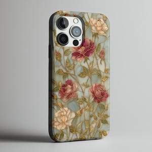 May include: A phone case featuring a floral design with red, pink, and cream-colored roses. The roses are set against a light blue background with gold-colored stems and leaves. The case has a black border and a camera cutout.