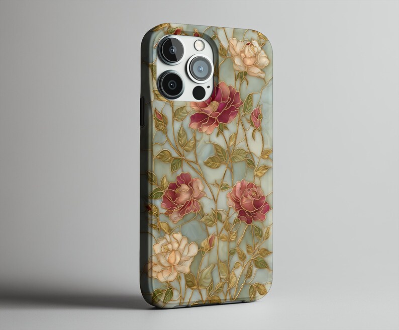 May include: A phone case featuring a floral design with red, pink, and cream-colored roses. The roses are set against a light blue background with gold-colored stems and leaves. The case has a black border and a camera cutout.