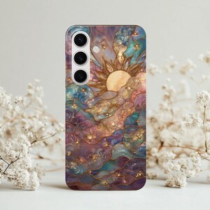 Puede incluir: Funda de tel&eacute;fono con un dise&ntilde;o celestial con un sol, estrellas y nubes en tonos morados, azules y dorados. La funda tiene un acabado brillante y un recorte para la c&aacute;mara.