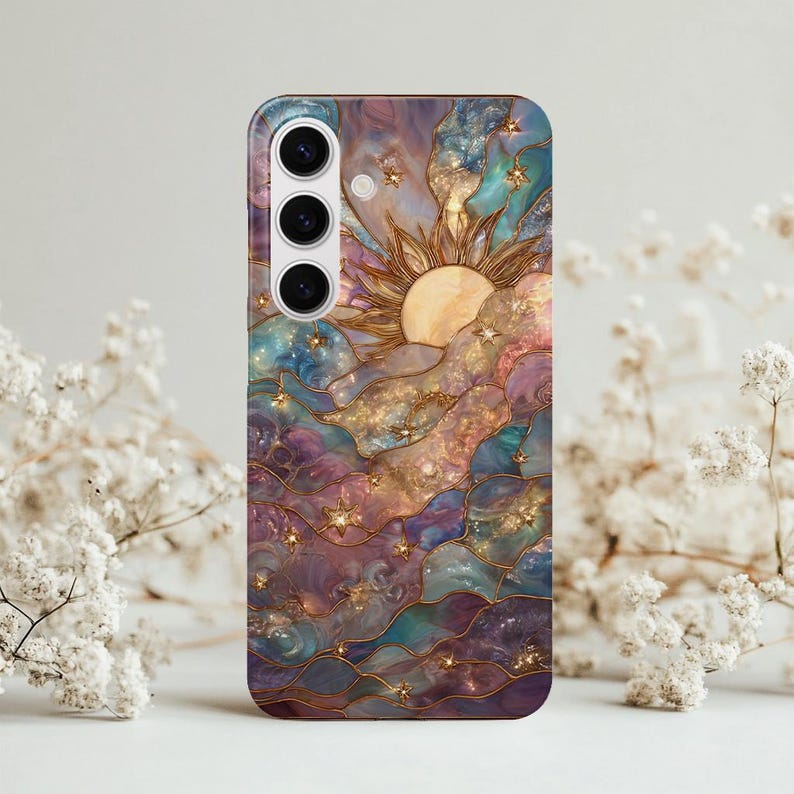 Puede incluir: Funda de tel&eacute;fono con un dise&ntilde;o celestial con un sol, estrellas y nubes en tonos morados, azules y dorados. La funda tiene un acabado brillante y un recorte para la c&aacute;mara.