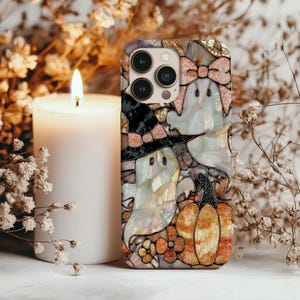 May include: A decorative phone case featuring a Halloween theme. The case has a mosaic design with images of ghosts, a witch, and a pumpkin. The case has a pearlescent finish with gold and orange accents.
