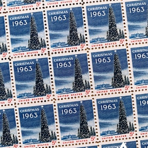 May include: A sheet of vintage Christmas stamps from 1963 featuring a blue and white illustration of a Christmas tree with a star on top. The stamps are from the United States Postal Service and each stamp has the text "Christmas 1963" and "United States 5c".