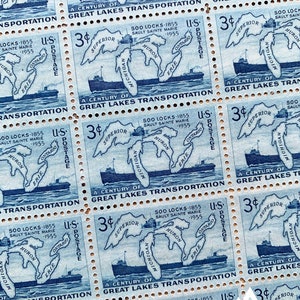 May include: A blue and white postage stamp with a map of the Great Lakes and a ship. The stamp reads "A Century of Great Lakes Transportation" and "3¢ U.S. Postage".