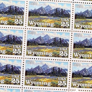 May include: A sheet of 25-cent US postage stamps featuring a scenic landscape of mountains and trees. The stamps are from 1890 and depict the state of Wyoming.