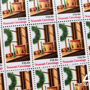 May include: A sheet of vintage Christmas stamps featuring a red and white toy drum, a green wreath, and a window with a wooden frame. The stamps are all marked "USA 15c" and "Season's Greetings".