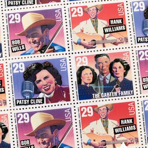 May include: A collection of vintage US postage stamps featuring country music legends. The stamps feature Patsy Cline, Bob Wills, Hank Williams, and The Carter Family. Each stamp has a red, white, and blue color scheme and features a portrait of the musician or group. The stamps are all marked with the year 1923-1953 and the denomination 29.