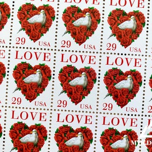 May include: A sheet of 10 US postage stamps featuring a white dove surrounded by red roses in the shape of a heart. Each stamp has the word "LOVE" printed in red and the denomination "29" printed in black.