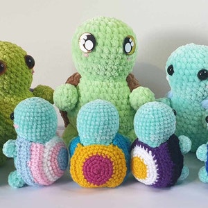 May include: A group of eight crocheted turtle plushies. The turtles are all different colours and have different patterns on their shells. The largest turtle is green and has big eyes. The other turtles are smaller and have different colours, including blue, brown, pink, yellow, and purple.
