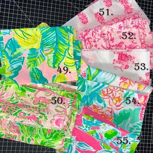 May include: A collection of colorful patterned fabric swatches. The fabrics feature tropical leaf, floral, and pineapple designs in shades of pink, green, yellow, and blue. The swatches are numbered 49 through 55.