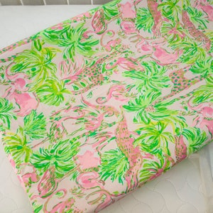 May include: Pink and green fabric with a tropical print featuring palm trees, flamingos, and giraffes.