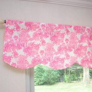May include: Pink and white scalloped valance with a floral pattern. The valance is made of a lightweight fabric and has a simple, elegant design.