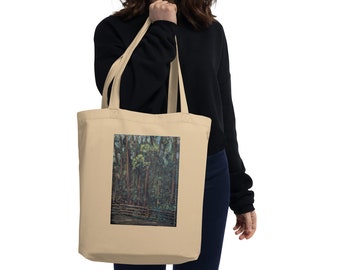 May include: A beige tote bag with a forest scene printed on the front. The scene features a group of trees with green leaves and a wooden fence in the foreground.