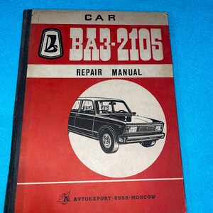 Puede incluir: Un manual de reparación de automóviles vintage con una cubierta roja y blanca. La cubierta presenta el texto "CAR", "BA3-2105" y "REPAIR MANUAL". Una ilustración en blanco y negro de un coche está en un círculo blanco. La parte inferior de la cubierta dice "AVTOEXPORT-USSR-MOSCÚ".