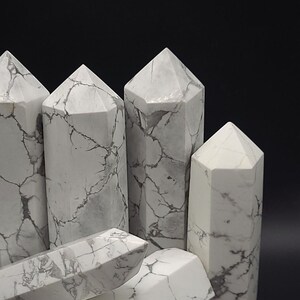 May include: Five white howlite crystal points with a marbled pattern. The crystals are arranged in a cluster, with some overlapping.