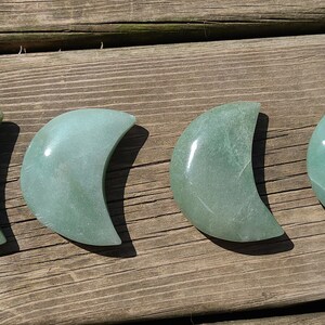 Pode incluir: Quatro pedras polidas em forma de lua crescente verde sobre uma superf&iacute;cie de madeira.