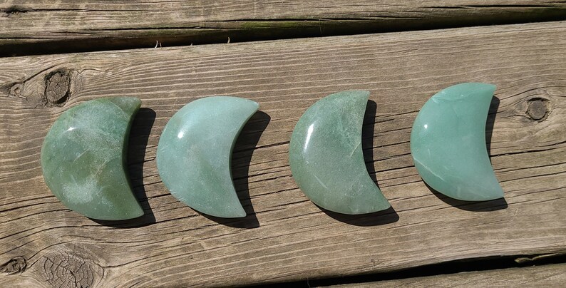 Pode incluir: Quatro pedras polidas em forma de lua crescente verde sobre uma superf&iacute;cie de madeira.