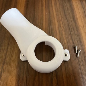 May include: A white 3D-printed plastic component with a curved neck and a circular opening. It has a mounting base with two holes and is accompanied by two small screws. The object is on a wooden surface.