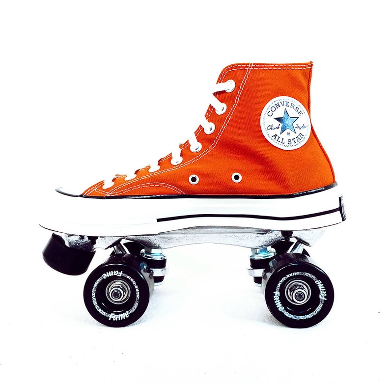 May include: Orange Converse high-top sneakers on roller skates with black wheels. The sneakers have a white sole and a blue star logo with the text "Chuck Taylor All Star".