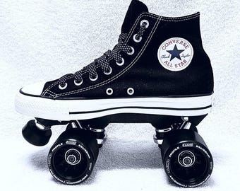 May include: A black high-top sneaker converted into a roller skate with four black wheels. The shoe features white laces, a white rubber toe cap, and a circular white Converse All Star patch. The wheels are labeled 93a/62mm.