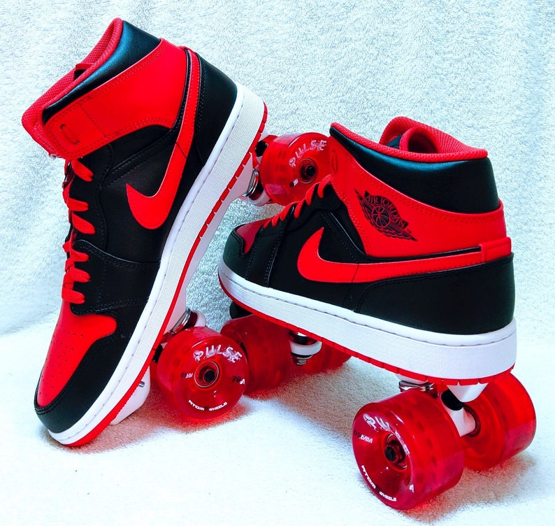 May include: A pair of black and red roller skates with red wheels. The skates have a black and red high-top design with the word "PULSE" on one of the wheels.