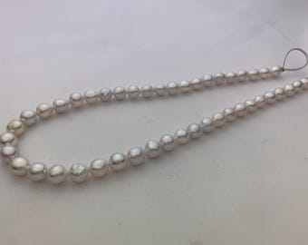 May include: A strand of white pearls strung together on a thin string. The pearls are all the same size and shape, and they have a smooth, glossy finish.