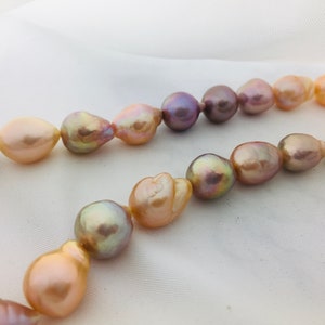 May include: A strand of baroque pearls in shades of pink, peach, and lavender. The pearls are irregular in shape and have a natural luster.