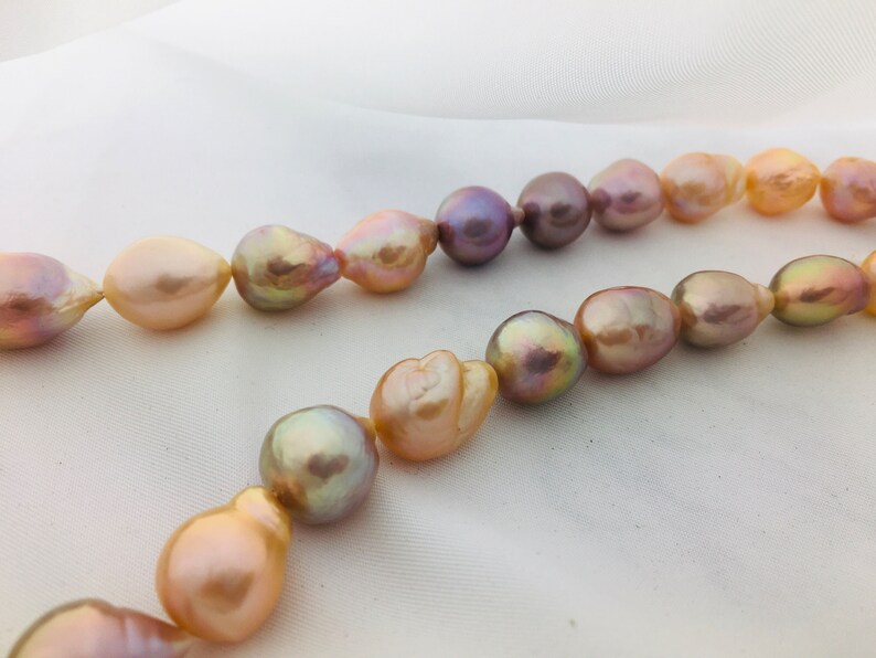 May include: A strand of baroque pearls in shades of pink, peach, and lavender. The pearls are irregular in shape and have a natural luster.